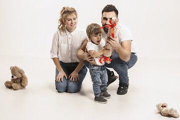 Image showing happy family with kid sitting together and smiling at camera isolated on white