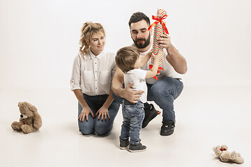 Image showing happy family with kid sitting together and smiling at camera isolated on white