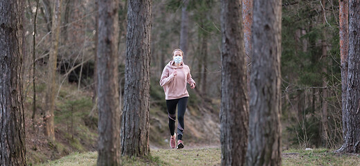 Image showing Corona virus, or Covid-19, is spreading all over the world. Portrait of caucasian sporty woman wearing a medical protection face mask while running in nature.