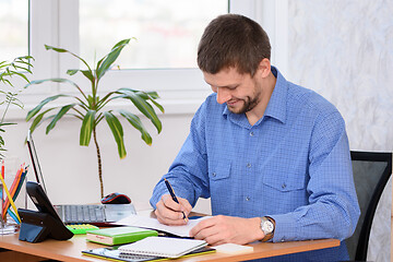 Image showing Successful office employee adjusts the report while sitting at his workplace