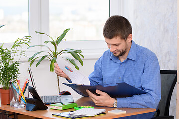 Image showing Office clerk reads documents in a folder