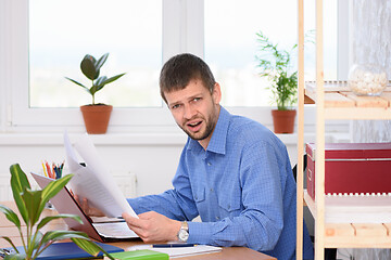 Image showing The office employee in a shocked state reads business papers and looked into the frame.