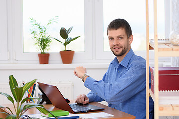 Image showing A business man checks the time with a wrist watch and looked into the frame