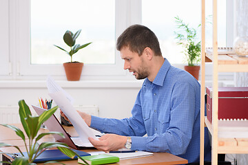 Image showing An office employee is reading business papers in shock