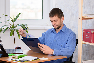 Image showing Business man reads a printed report in a folder