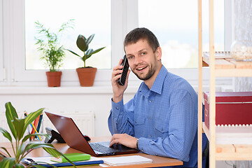 Image showing Happy young man talking on the phone and looking in the frame