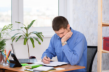 Image showing Pensive employee reads business papers in the office