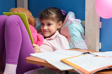 Image showing Satisfied child relaxes with tablet in hand from lessons