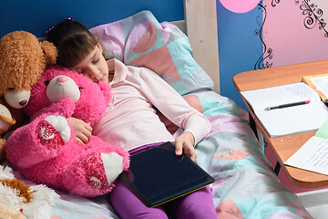 Image showing a girl with a tablet in her hand who was asleep among the toys