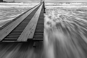 Image showing Black and white photo - surf in the storm after sunset, pier, long exposure