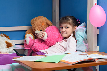 Image showing Girl\'s lip lying on the bed with soft toys and textbooks in the foreground