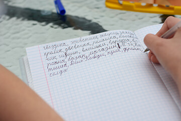 Image showing The child learns to write letters correctly and writes various words in Russian in a notebook