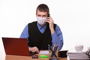 Image showing The clerk in a medical mask is talking on the phone and looked in the frame