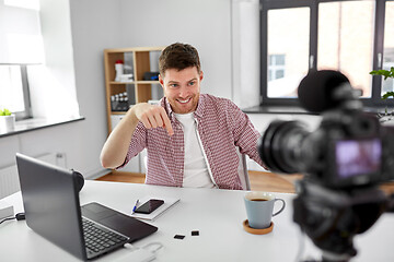 Image showing male blogger with camera videoblogging at home