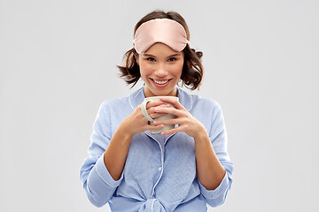 Image showing woman in pajama and sleeping mask drinking coffee