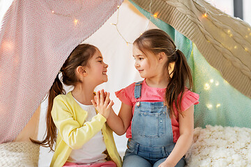 Image showing happy girls lying in kids tent and talking at home