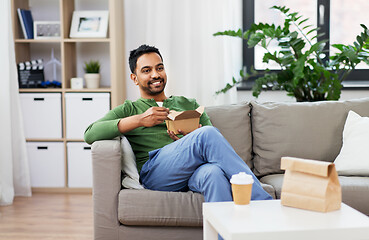 Image showing smiling indian man eating takeaway food at home