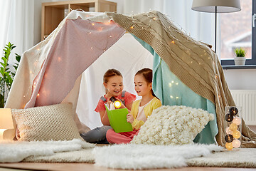 Image showing happy girls reading book in kids tent at home