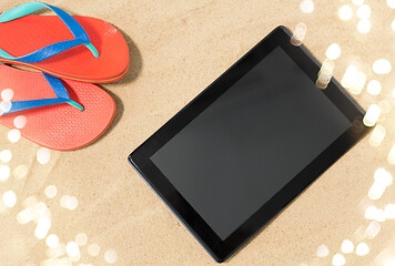 Image showing tablet computer and flip flops on beach sand