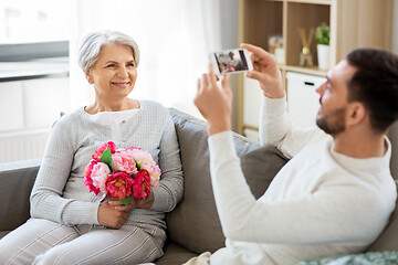 Image showing adult son photographing senior mother at home