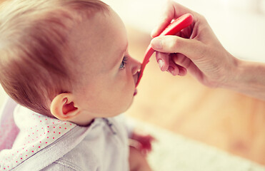 Image showing hand with spoon feeding little baby at home