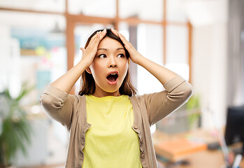 Image showing stressed asian woman holding to her head at office