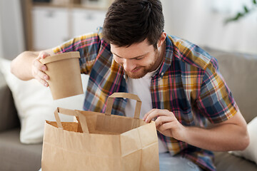 Image showing smiling man unpacking takeaway food at home