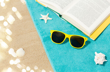 Image showing sunglasses and book on beach towel on sand