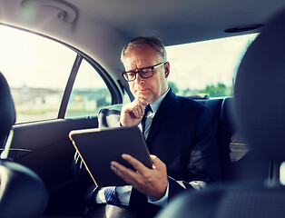 Image showing senior businessman with tablet pc driving in car