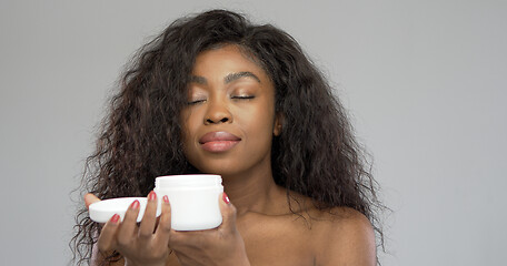 Image showing Black woman smelling cream with closed eyes