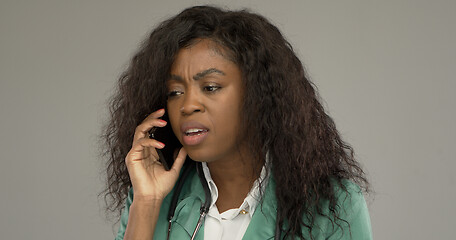 Image showing Displeased black doctor answering phone call