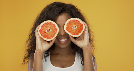 Image showing Excited ethnic woman playing with grapefruit