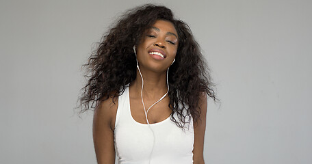Image showing Black woman listening to music and smiling