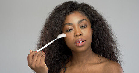 Image showing African American woman applying makeup