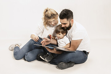 Image showing happy family with kid sitting together and smiling at camera isolated on white