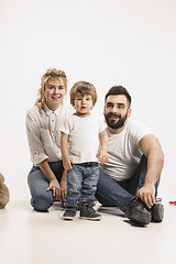 Image showing happy family with kid sitting together and smiling at camera isolated on white