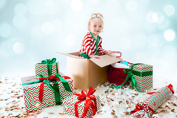 Image showing Cute baby girl 1 year old sitting at box over Christmas background. Holiday season.