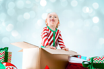 Image showing Cute baby girl 1 year old sitting at box over Christmas background. Holiday season.