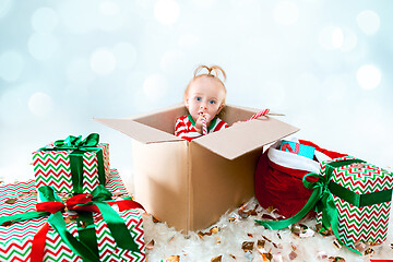 Image showing Cute baby girl 1 year old sitting at box over Christmas background. Holiday season.