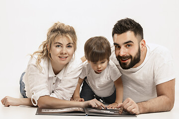 Image showing happy family with kid sitting together and smiling at camera isolated on white