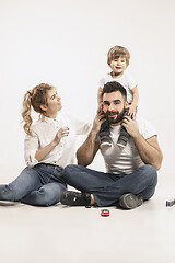 Image showing happy family with kid sitting together and smiling at camera isolated on white