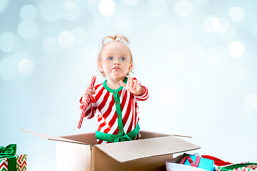 Image showing Cute baby girl 1 year old sitting at box over Christmas background. Holiday season.