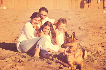 Image showing happy family playing with dog on beach