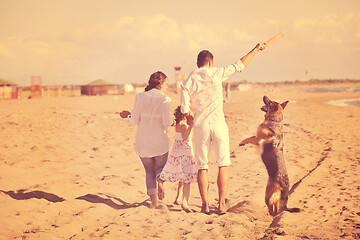 Image showing happy family playing with dog on beach