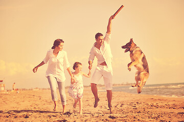 Image showing happy family playing with dog on beach