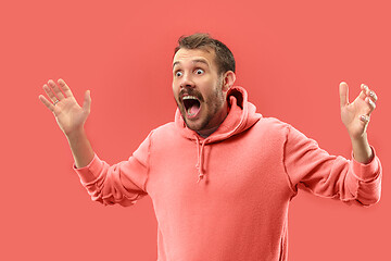 Image showing The young attractive man looking suprised isolated on coral background