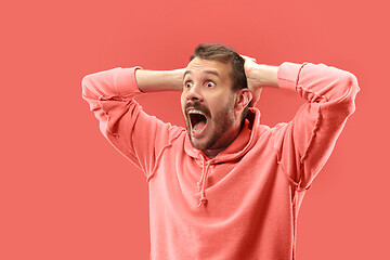 Image showing The young attractive man looking suprised isolated on coral background