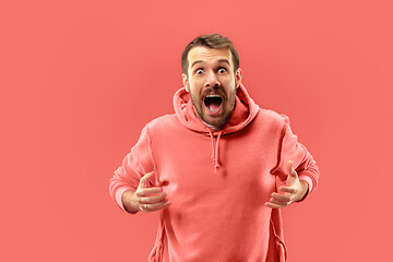 Image showing The young attractive man looking suprised isolated on coral background