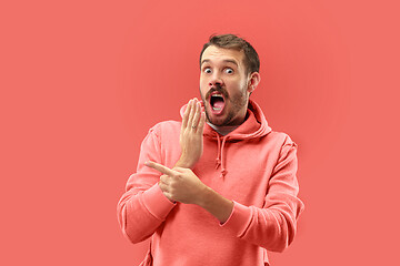 Image showing The young attractive man looking suprised isolated on coral background