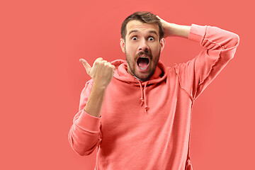 Image showing The young attractive man looking suprised isolated on coral background